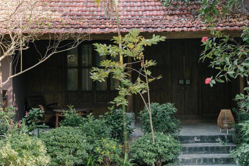 a house with a wooden door and some plants at TOKI Retreat Vân Long in Ninh Binh