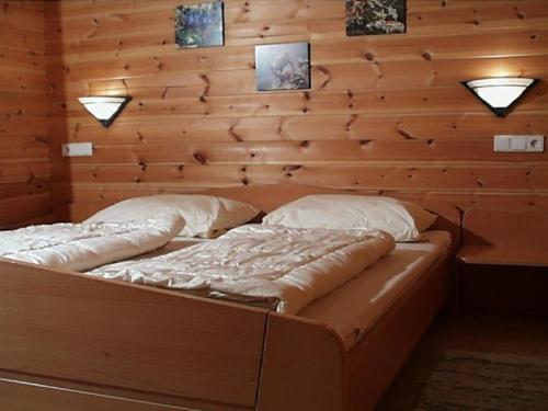 Cama en habitación con pared de madera en Ferienhaus Nr 17, Typ B, Feriendorf Jägerpark, Bayerischer Wald, en Viechtach