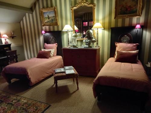 a bedroom with two beds and a mirror at Le Prieuré de l'Auxois in Alise-Sainte-Reine
