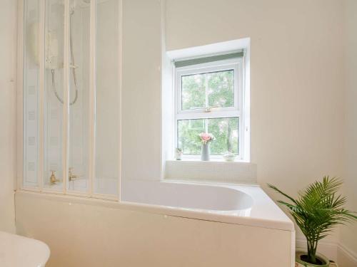 a white bathroom with a tub and a window at 4 Bed in Corwen 88868 in Corwen