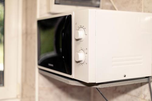 a white microwave oven hanging on a wall at Pysana hata in Volosyanka