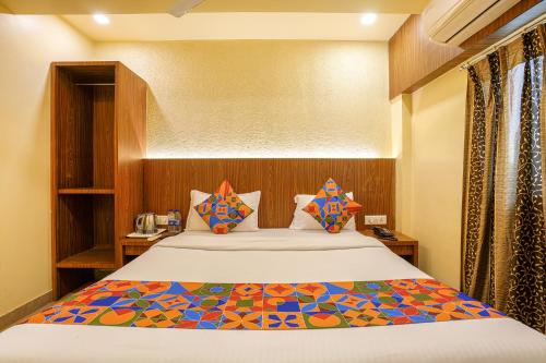 een slaapkamer met een groot bed en een kleurrijk dekbed bij FabExpress Swagatham Residency in Mumbai