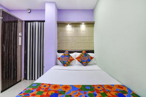 1 dormitorio con 1 cama grande y almohadas coloridas en FabExpress Laxmi Inn en kolkata