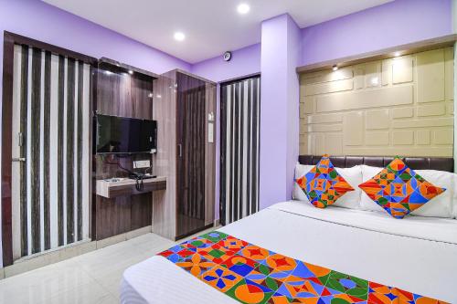 a bedroom with a bed with colorful pillows and a tv at FabExpress Laxmi Inn in kolkata