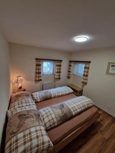 two beds in a bedroom with two windows at Haus Rizzi in Bivio