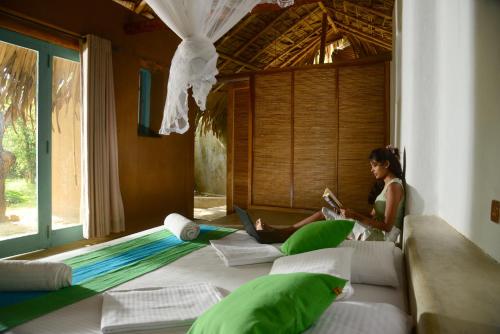 a woman sitting on a bed reading a book at Back of beyond - Wellness Retreat in Tangalle