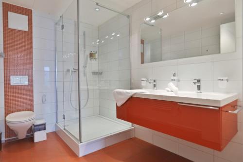 a bathroom with a shower and a sink and a toilet at Montreux Lake View Apartments and Spa - Swiss Hotel Apartments in Montreux