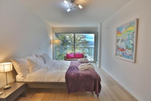 a bedroom with a bed and a chair and a window at Montreux Lake View Apartments and Spa - Swiss Hotel Apartments in Montreux
