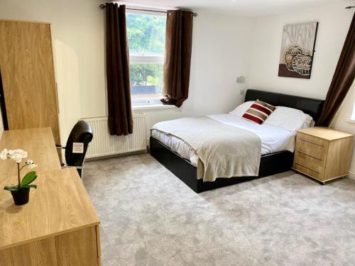Schlafzimmer mit einem Bett, einem Schreibtisch und einem Fenster in der Unterkunft Sapphire Suites in Reading
