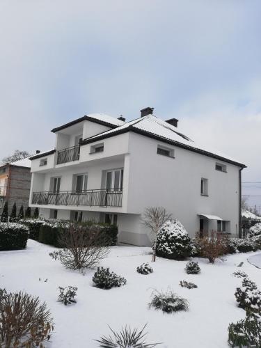 a large white building with snow on the ground at Przystań Przylasek in Krakow