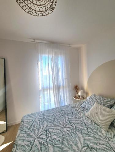 ein Schlafzimmer mit einem Bett mit blauer Decke und einem Fenster in der Unterkunft Moderne et charmant T2 in Villiers-le-Bel