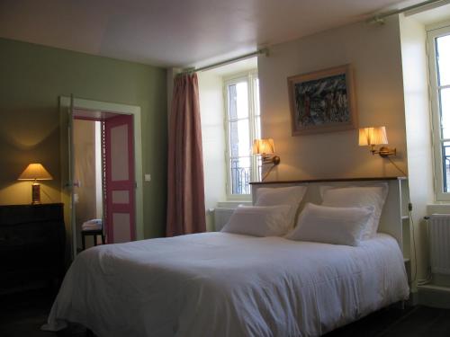 a bedroom with a bed with white sheets and windows at Chambres d'hôtes -B&B- La Bonneterie in Montaigut-le-Blanc
