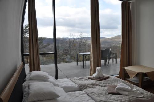 a bedroom with a bed and a large window at Üveghuta Vendégház in Vágáshuta