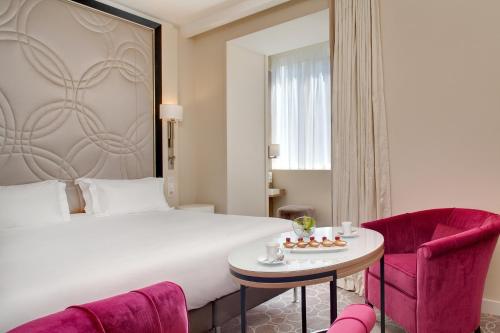 a hotel room with a bed and a table and chairs at Grand Hôtel Thalasso & Spa in Saint-Jean-de-Luz