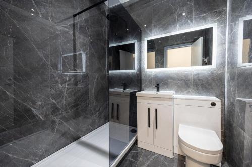 a bathroom with a toilet and two sinks and a shower at Stunning Bolton Abode - Cinema Experience - Parking in Bolton