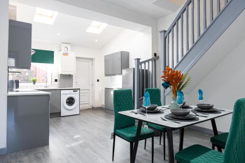 a kitchen and dining room with a table and green chairs at Bolton 2BR Cinema House, Free Parking, Fast WiFi, Comfortable Stay in Bolton