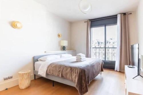 une chambre blanche avec un lit et une grande fenêtre dans l'établissement Avenue Montaigne Luxury Apartment 2BR 4P, à Paris