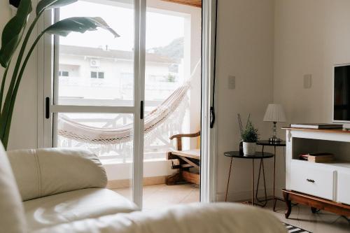 uma sala de estar com uma porta de vidro deslizante em Completo apartamento em Resort na beira da lagoa em Florianópolis