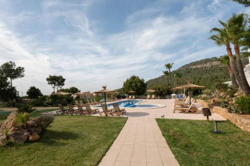 a resort with a pool and picnic tables and palm trees at Apartamentos Blanco Sol in Cala Vadella