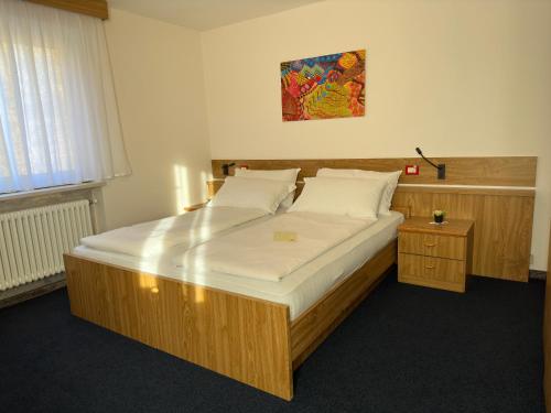 a bedroom with a large wooden bed with white sheets at PANORAMA SportHOTEL in Folgaria