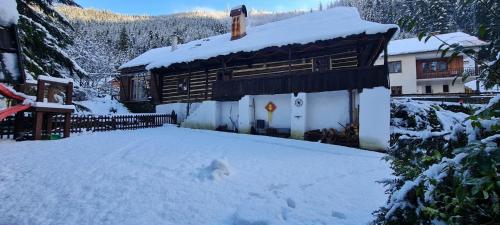 Cabaña de madera con nieve en el suelo en Atelier Eliska, en Staré Hory