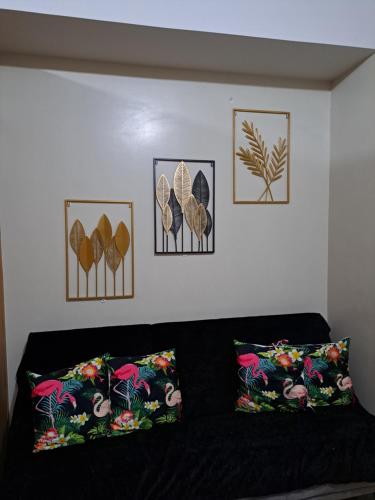 a black couch with four pictures on the wall at Shell Residences in Manila
