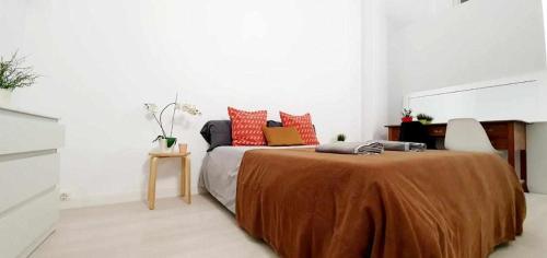 1 dormitorio con 1 cama grande con almohadas de color naranja en Hostal Urban Basic, en Hospitalet de Llobregat