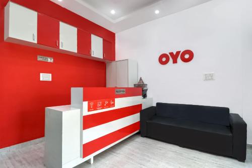 Cette chambre dispose d'un canapé et d'un mur rouge. dans l'établissement OYO 71370 White House, à Garhi Harsāru