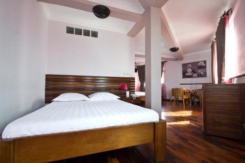 a bedroom with a bed with white sheets and a table at Anjary Hotel Antananarivo in Antananarivo