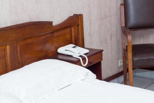 a phone sitting on a table next to a bed at Anjary Hotel Antananarivo in Antananarivo