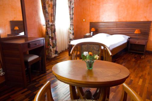 a bedroom with a table and a bed and a table with flowers at Anjary Hotel Antananarivo in Antananarivo