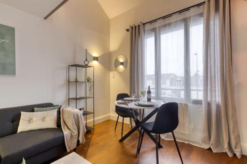 een woonkamer met een bank en een tafel met stoelen bij Chaleureux duplex 30min de Paris in Corbeil-Essonnes