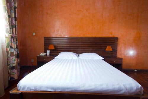 a bedroom with a large white bed with two lamps at Anjary Hotel Antananarivo in Antananarivo