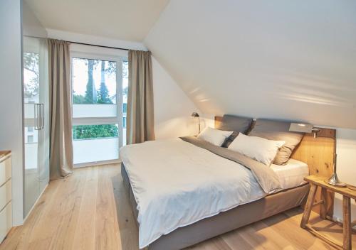 um quarto com uma cama e uma grande janela em Sunshine Suite - mit Meerblick em Timmendorfer Strand