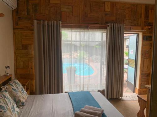 - une chambre avec un lit et une fenêtre avec une piscine dans l'établissement Nkwasi Lodge, à Parys