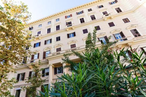 ein weißes Gebäude mit Bäumen davor in der Unterkunft V10 GUESTHOUSE - Vanvitelli 10 in Neapel