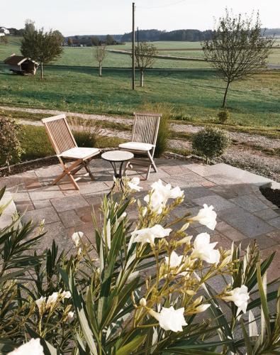 two chairs and a table in a garden with flowers at Ferienwohnung Polsing 19 in Palling