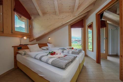 twee bedden in een kamer met houten plafonds en ramen bij Volga Loira Senna - Happy Rentals in Livigno