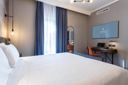 a hotel room with a large white bed and a desk at AXYHOTELS InnStyle Milano in Milan