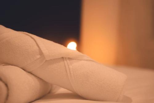 - une serviette blanche sur un lit avec une bougie dans l'établissement Le Verlaine, T4 en triplex, à Tours