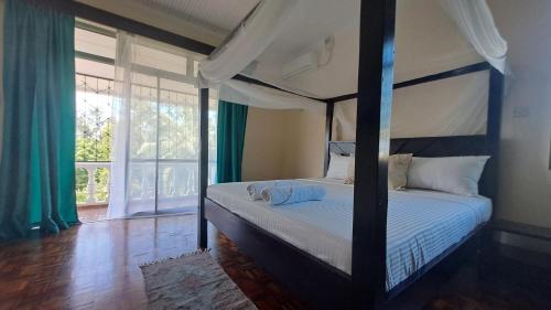 a bedroom with a canopy bed and a large window at Ary Homestay Nyali - On Corral Drive in Mombasa