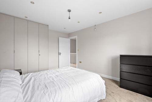 a white bedroom with a bed and a dresser at Stylish Sparkling Brand New 3 bed house in Heston