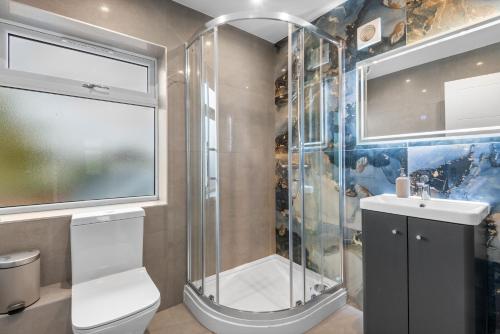 a bathroom with a shower and a toilet and a sink at Stylish Sparkling Brand New 3 bed house in Heston