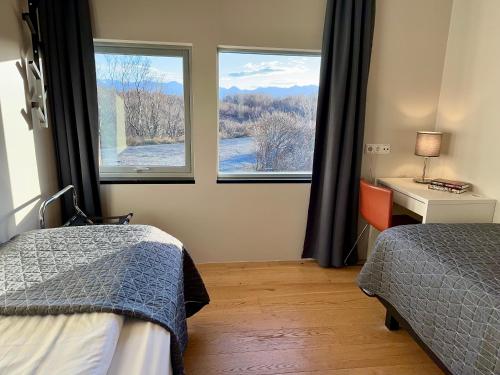 1 dormitorio con 2 camas, escritorio y 2 ventanas en Bakki, en Jarðlangsstaðir