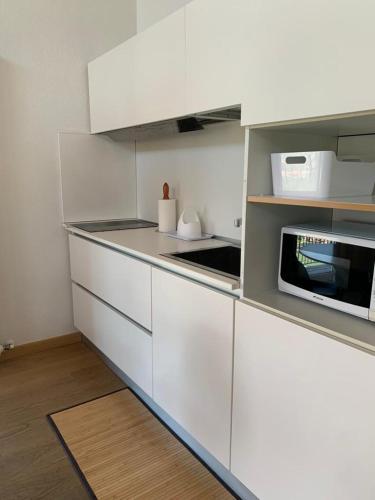 a kitchen with white cabinets and a microwave at Hotel Isola Verde in Nago-Torbole