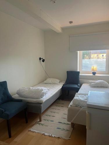 duas camas num quarto com duas cadeiras e uma janela em Cilla och Smillas AB em Malmo