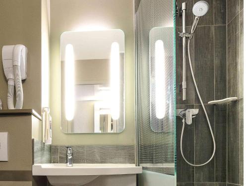 a bathroom with a shower and a sink and a mirror at Ibis Lyon Villefranche Sur Saone in Limas