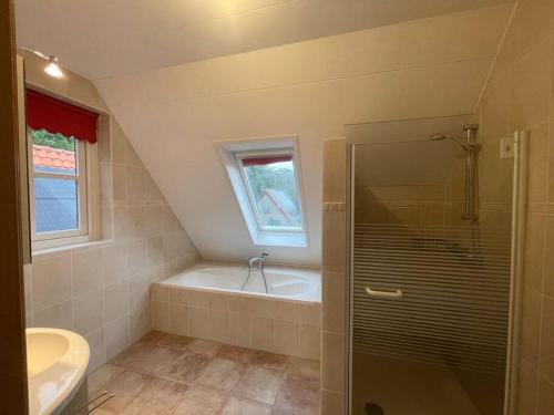 een badkamer met een douche, een bad en een wastafel bij Vakantiehuis Aldubo in Den Burg