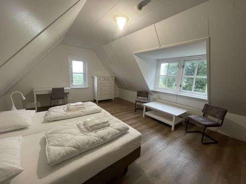 a attic bedroom with two beds and a desk at Vakantiehuis Aldubo in Den Burg