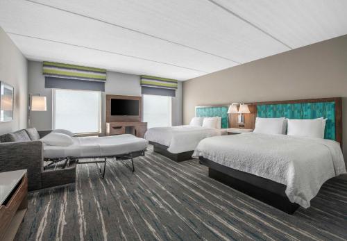 a hotel room with two beds and a couch at Hampton Inn & Suites Dallas-Allen in Allen